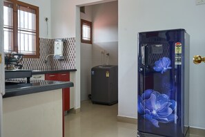Een keuken met een koelkast, een boiler en een raam.
