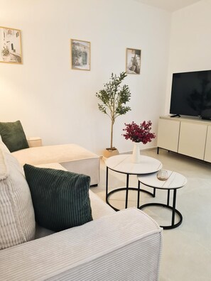 A modern living room with a sofa, a coffee table, a potted plant, and a television. - Vrbo Property (Tribunj)