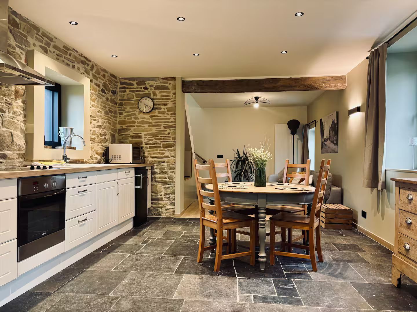 A kitchen with a stone wall, wooden dining table, and modern appliances.