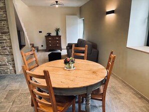 Un coin repas comprenant une table ronde en bois, quatre chaises en bois et un vase avec des fleurs.