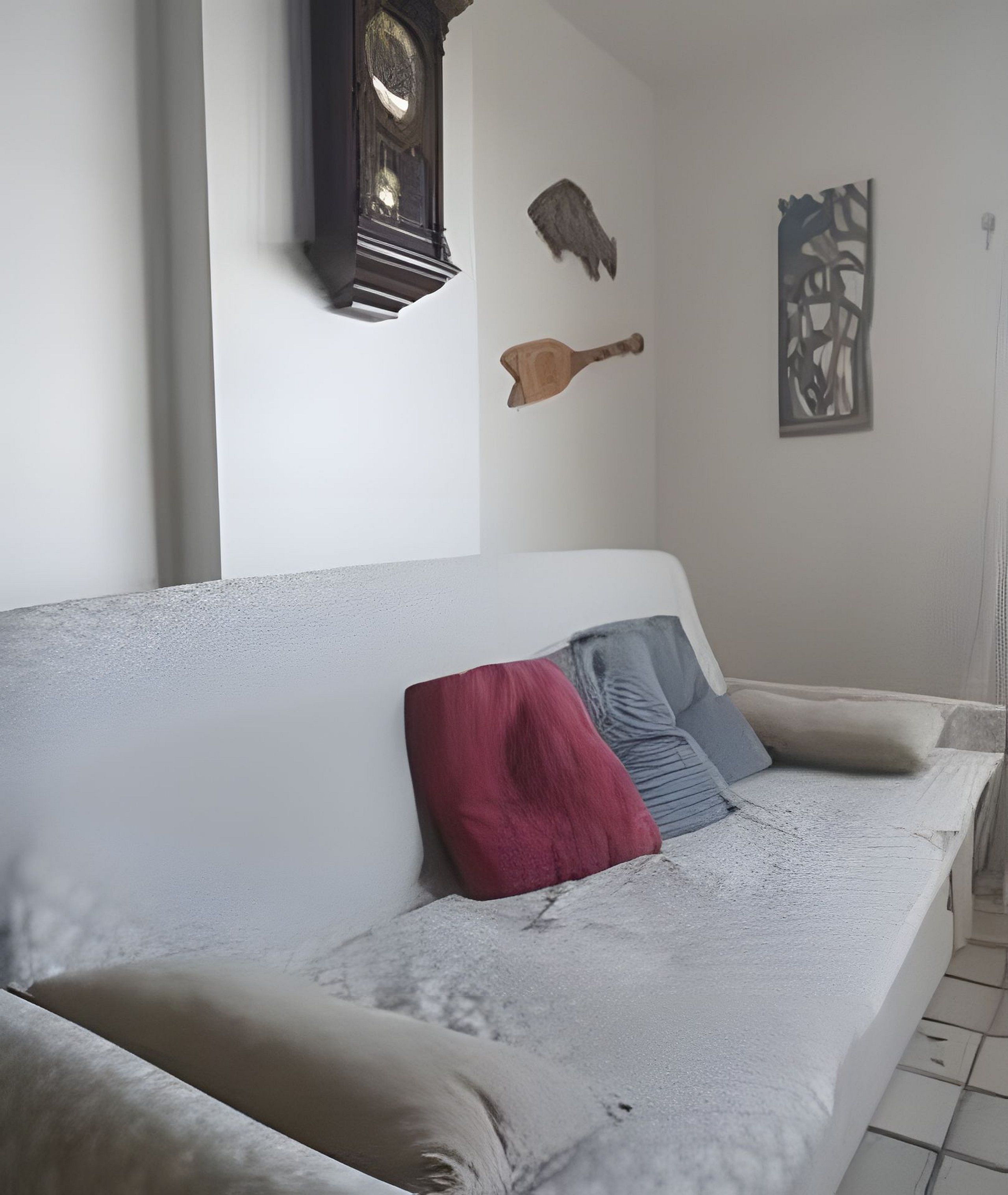 A living room with a sofa, pillows, a clock, and wall art.