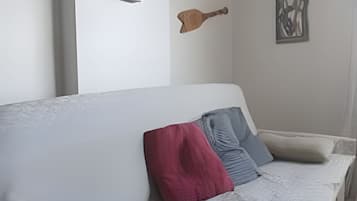 A living room with a sofa, pillows, a clock, and wall art.