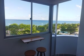 A room with a large window offering a view of the sea and greenery. - Sea Tower duplex beira-mar (Maceió)