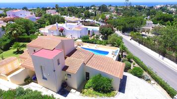 A residential area with a swimming pool, white buildings, and a view of the sea.