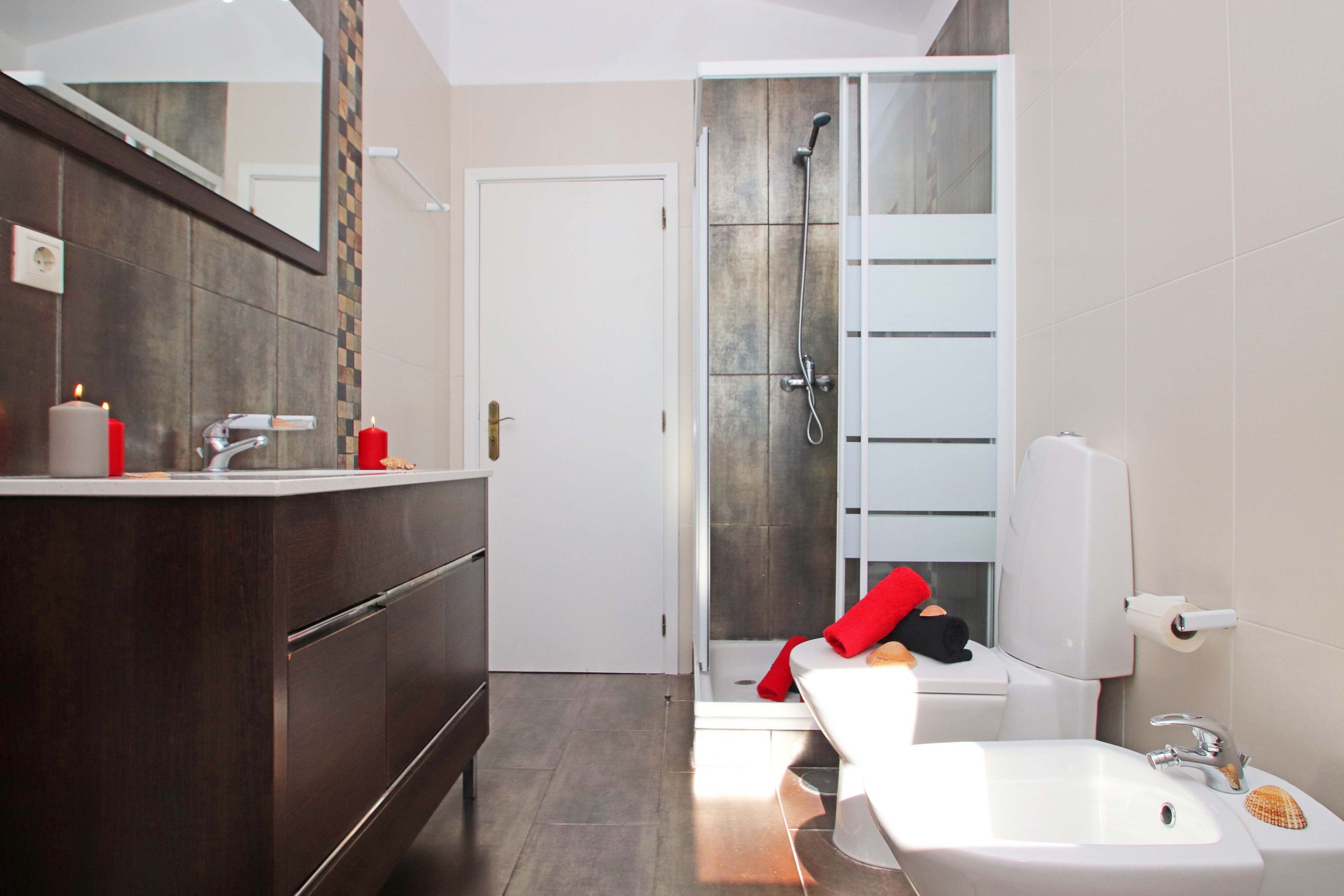 A modern bathroom with a shower, toilet, and sink.