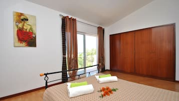 A bedroom with a bed, a large wardrobe, a painting on the wall, and a window with curtains.