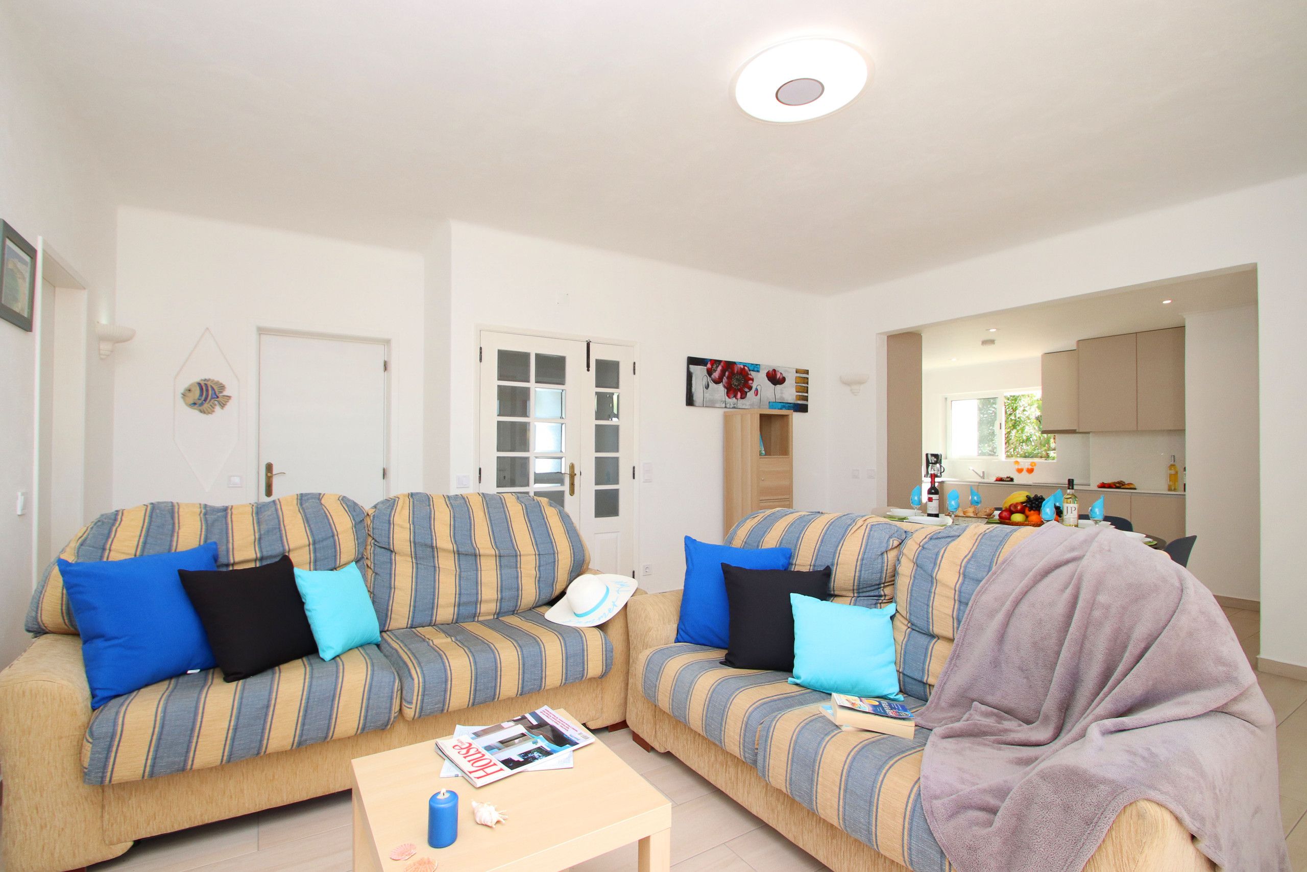 A living room with two sofas, a coffee table, and a kitchen area in the background.