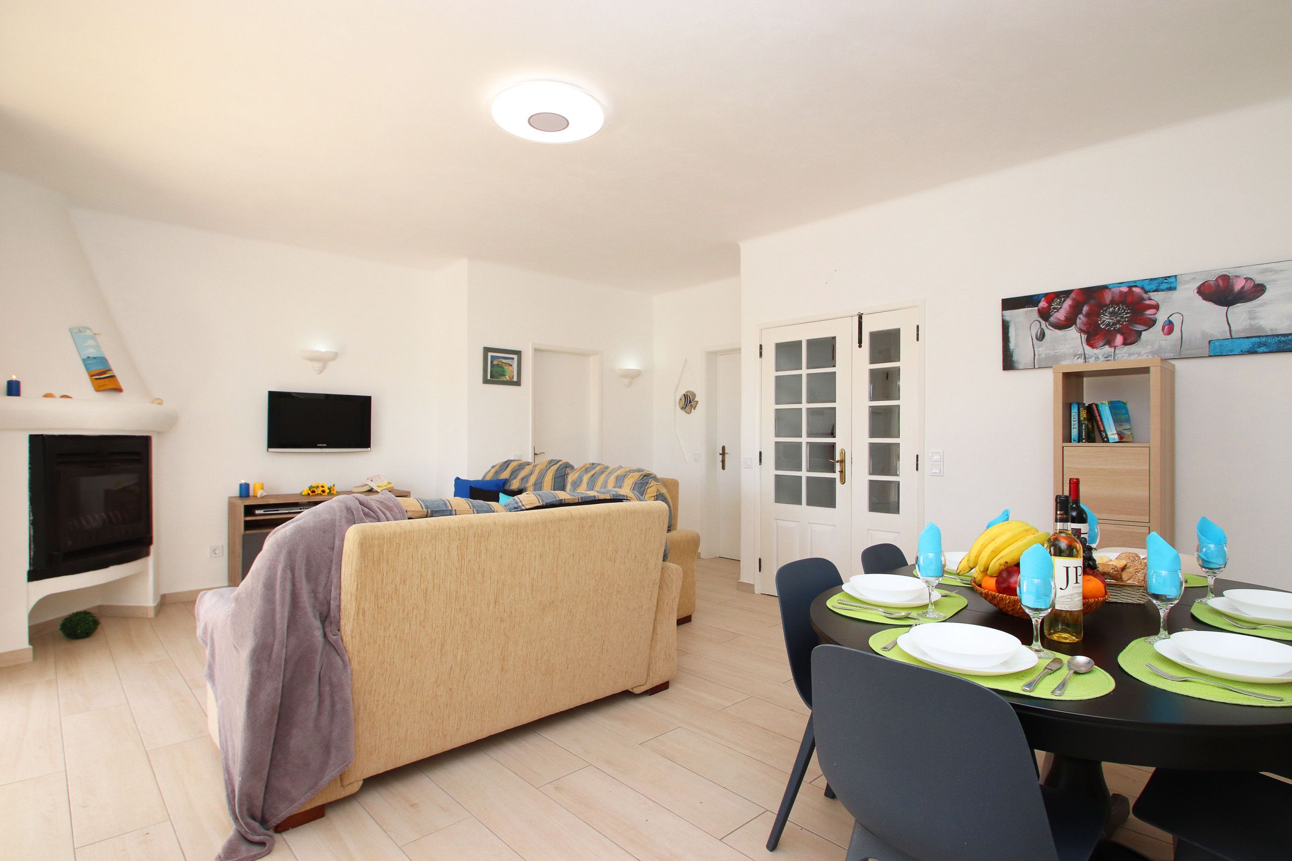 Un salon moderne avec un canapé, un téléviseur à écran plat et un coin repas préparé pour le dîner.