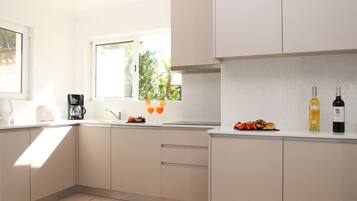 A modern kitchen with a window, a coffee maker, and two bottles of wine on the counter.