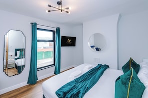 A modern bedroom with a bed, a large mirror, a ceiling light fixture, and a window with curtains. - Contractors | Families & Leisure | 3 Bed | Sleeps 6 | Bootle (Bootle)