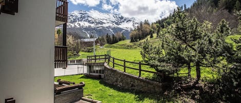 A mountain landscape with a building featuring a balcony and a stone wall.