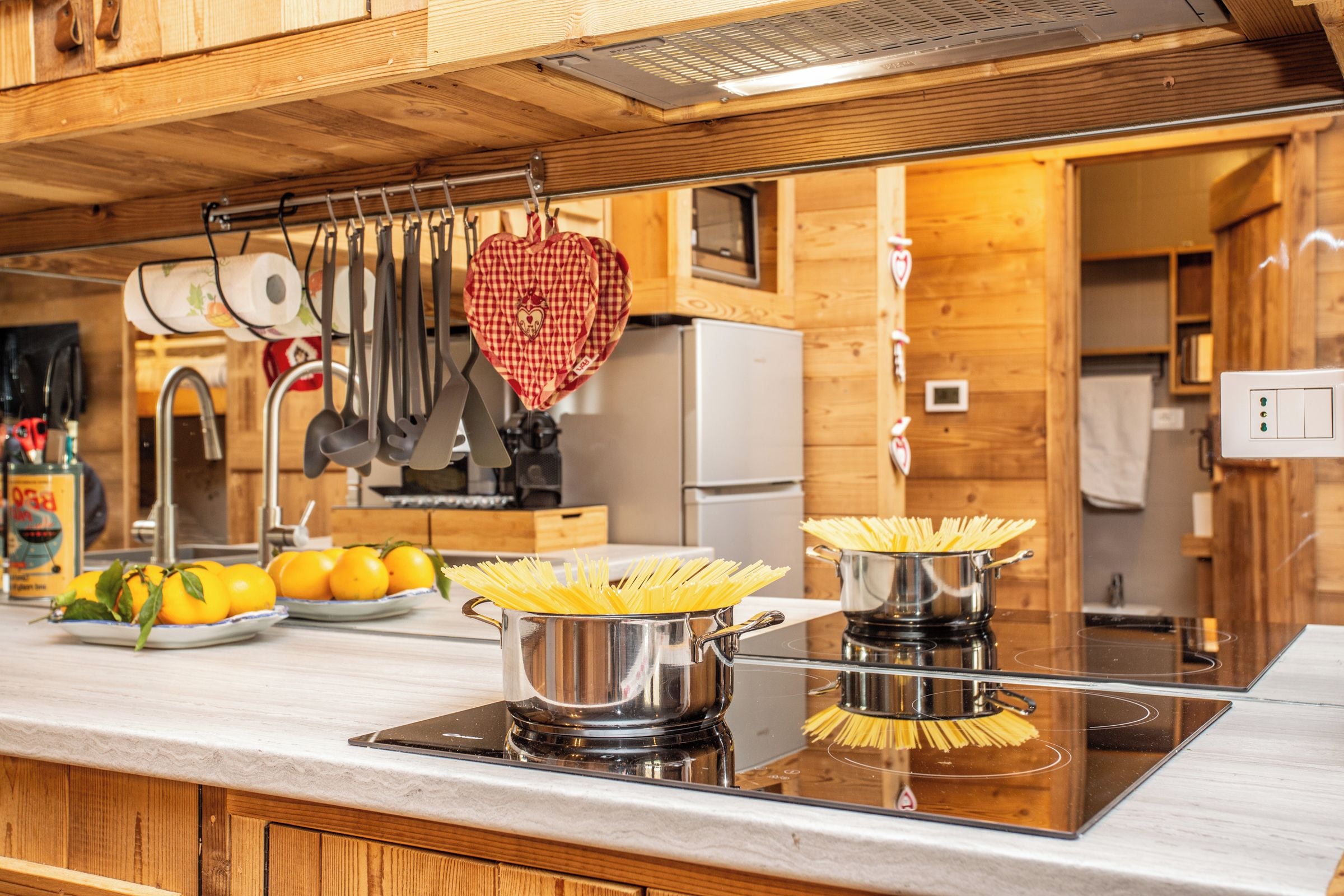 Una cocina con armarios de madera, estufa de acero inoxidable y un colgador para ollas con forma de corazón.