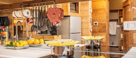 A kitchen with wooden cabinets, a stainless steel stove, and a heart-shaped hanging pot holder.