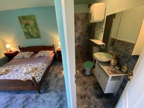 A bedroom with a bed, nightstand, and lamp, and a bathroom with a sink, toilet, and shower. - Villa Agata Ground Floor With Pool & Sauna (Rab)