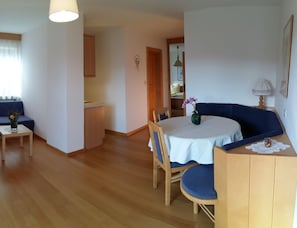 A compact living space with a dining area, a kitchenette, and a seating area with a blue sofa and a small table. - Holiday Apartment With 1 Bedroom (Meltina)