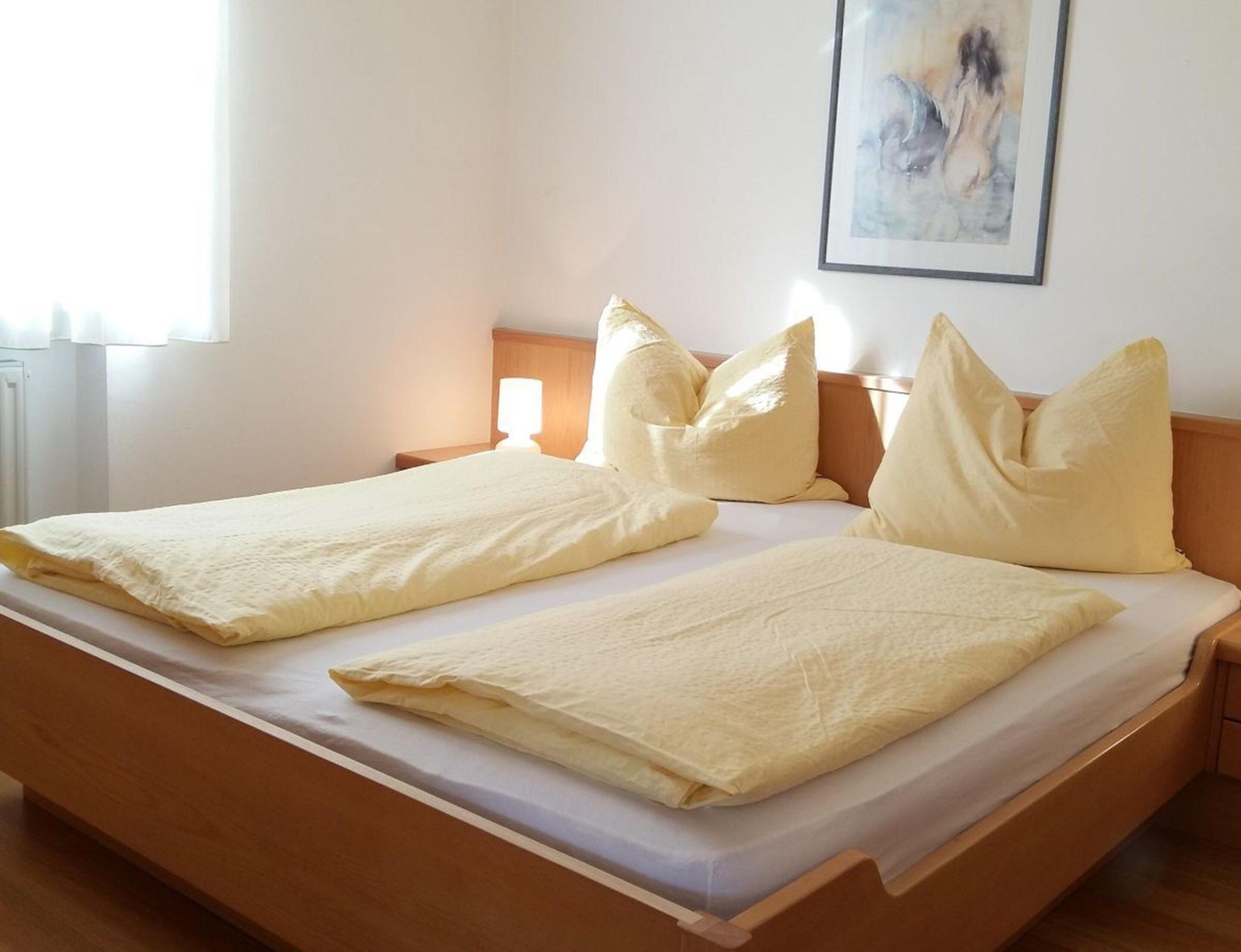 A double bed with two pillows and a bedside table with a lamp.
