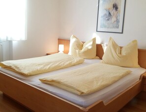 A double bed with two pillows and a bedside table with a lamp. - Holiday Apartment With 1 Bedroom (Meltina)