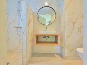 A bathroom with a marble wall, a wooden vanity, a sink, a mirror, and a shower. - Holiday Home With 3 Bedrooms (Callantsoog)