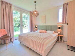 A bedroom with a bed, a chair, a bedside table, a lamp, and a window. - Holiday Home With 3 Bedrooms (Callantsoog)