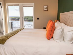 A hotel room with a bed, a view of the sea, and a framed picture on the wall. - Holm (Harris)