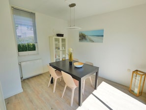 Ein Essbereich mit Tisch, Stühlen, einem Schrank und einem Bild an der Wand.