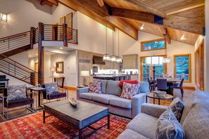A spacious living area with a high ceiling, a staircase, and a view of the kitchen. - Ski right out of the back door to a private trail on Deer Valley Resort! (Deer Valley)