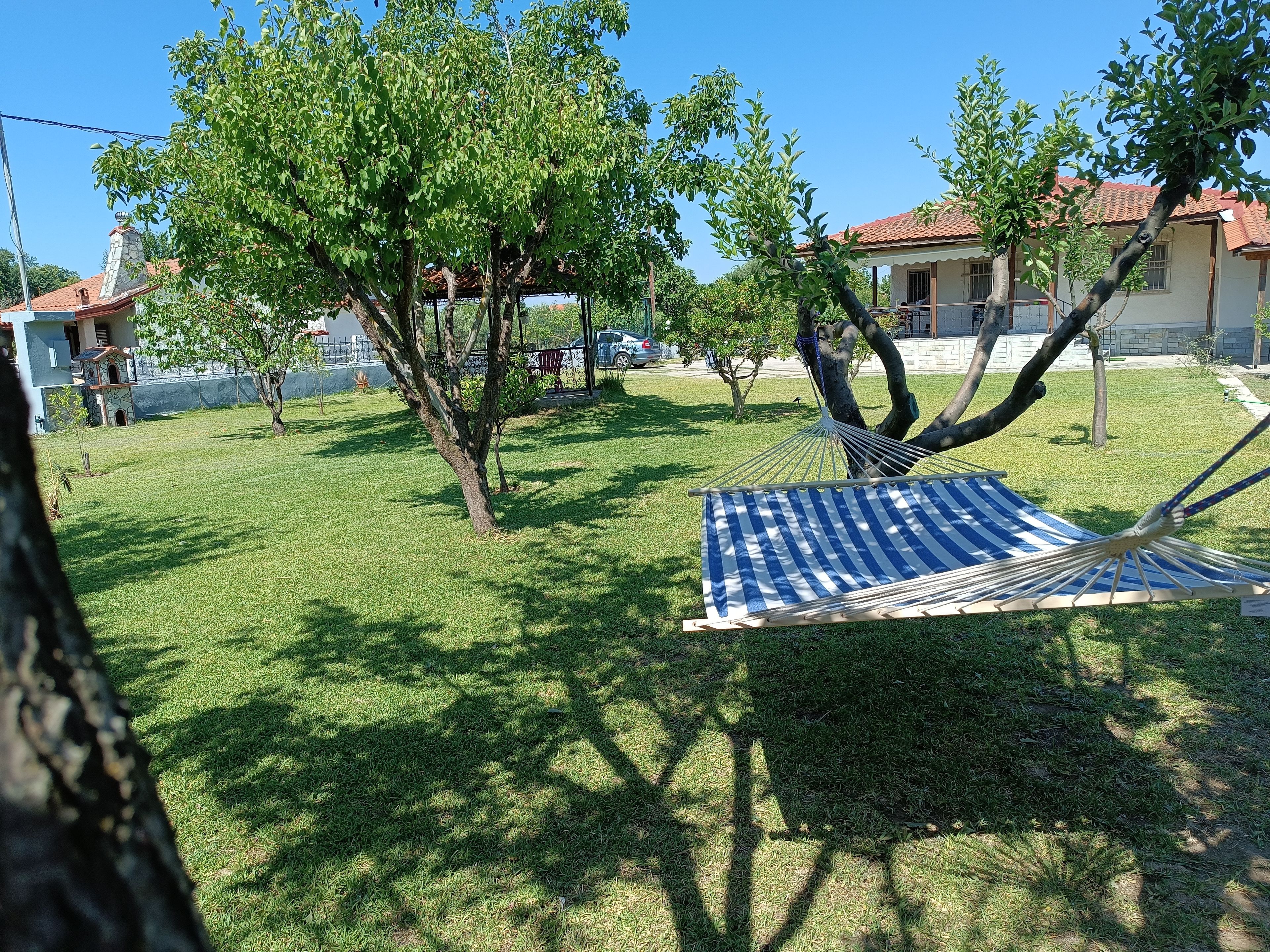 A hammock on a grassy lawn with trees and a building in the background.
