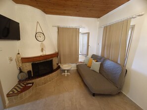 A living room with a fireplace, a sofa, a flat-screen TV, and a clock on the wall.