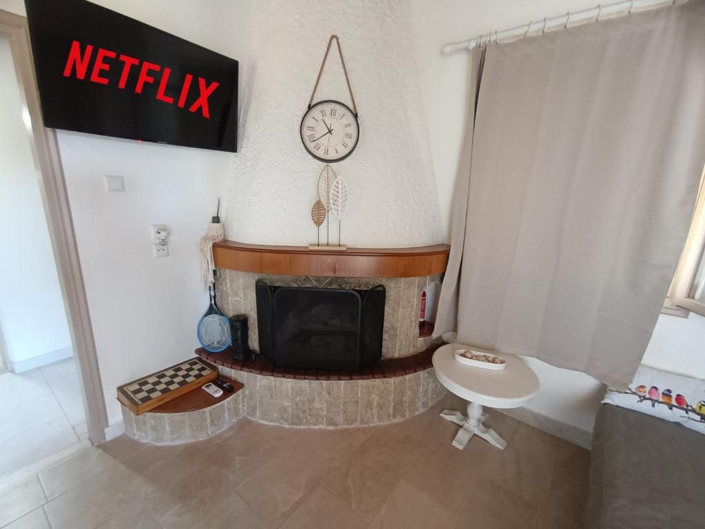 Una sala de estar con chimenea, un televisor montado encima, un reloj y una pequeña mesa con un tablero de ajedrez.