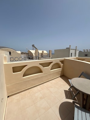 A rooftop terrace with a table and chairs, a water tank, and a view of the sky. - Apartment 'Maisonette - 101' with Sea View, Wi-Fi and Air Conditioning (Εμπορείο)
