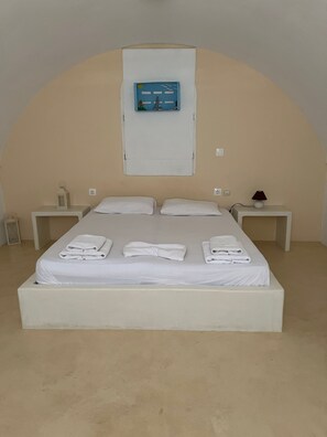 A single-bed room with a white bed, two bedside tables, a wall-mounted TV, and a small lamp. - Apartment 'Maisonette - 105' with Sea View, Wi-Fi and Air Conditioning (Εμπορείο)