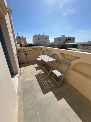 An outdoor patio area with a table and chairs, a drying rack, and a view of neighboring buildings. - Apartment 'Maisonette - 105' with Sea View, Wi-Fi and Air Conditioning (Εμπορείο)