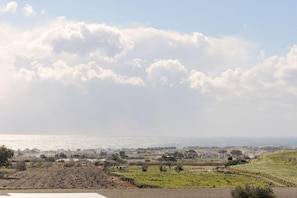 Eine Küstenlandschaft mit Blick auf das Meer, Felder und entfernte Gebäude.