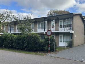 Ein zweigeschossiges Wohngebäude mit einem Balkon im oberen Geschoss, einem Verbotsschild für Parken und einem gepflasterten Auffahrtsweg.