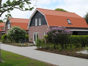 A modern residential building with a brick facade, a sloped roof, and a paved walkway leading to the entrance. - Dunopark 1-6 (Oostkapelle)