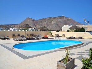 Una piscina con lettini e vista su una montagna.