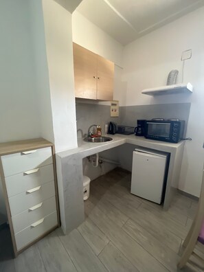 Eine kleine Küche mit Mikrowelle, kleinem Kühlschrank, Spüle und Schrank.