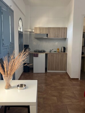 Eine kleine Küche mit weißer Arbeitsplatte, einem eingebauten Backofen und Holzschränken.