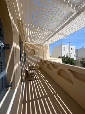 Ein Balkon mit einer Pergola, einem kleinen Tisch und einem Stuhl.
