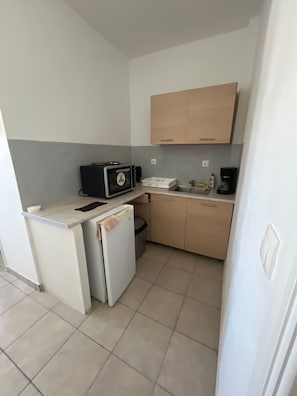 A compact kitchenette with a microwave, toaster, sink, and a small refrigerator. - Studio Apartment 'Triple Room - 103' with Sea View, Wi-Fi and Air Conditioning (Εμπορείο)