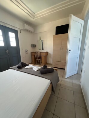 Ein Hotelzimmer mit einem Bett, einem Schreibtisch, einem Stuhl, einem Kleiderschrank und einer Tür.