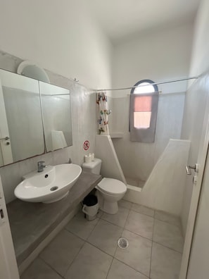 Ein kleines Badezimmer mit Waschbecken, Toilette und Dusche.