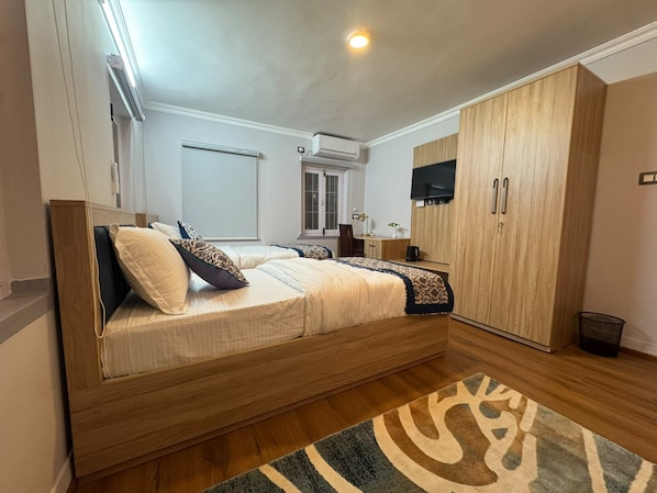 Un dormitorio con cama, armario y escritorio con silla.