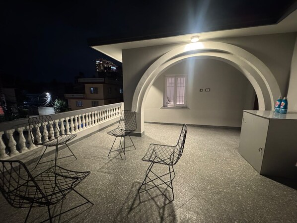 A rooftop terrace with a seating area, a small window, and a cabinet with bottles.