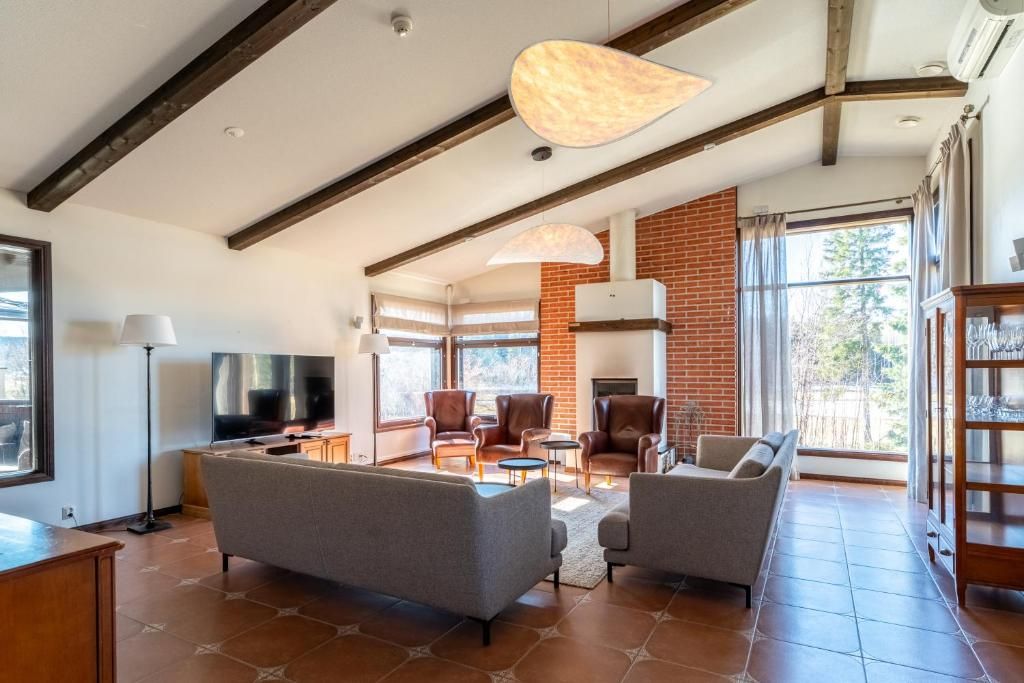 A spacious living room with a fireplace, comfortable seating, and large windows.