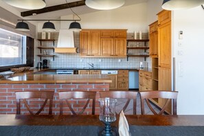 Eine moderne Küche mit Holzschränken, einer zentralen Kochinsel und Pendelleuchten.