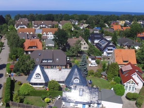 A residential area with houses, some with sloped roofs and others with flat roofs, surrounded by greenery and a clear sky. - Holiday Apartment With 1 Bedroom (Zingst)
