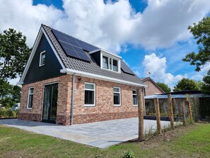 Ein modernes Haus mit Satteldach, Solaranlage und Backsteinfassade.