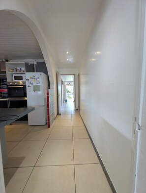 Ein Korridor mit einer Küchenzeile links, inklusive Kühlschrank, Mikrowelle und Backofen.