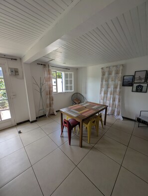 A room with a tiled floor, a table with chairs, a window with curtains, a fan, and a door with a thermostat. - Comfortable house for 6 guests in southern Réunion (Saint-Pierre)